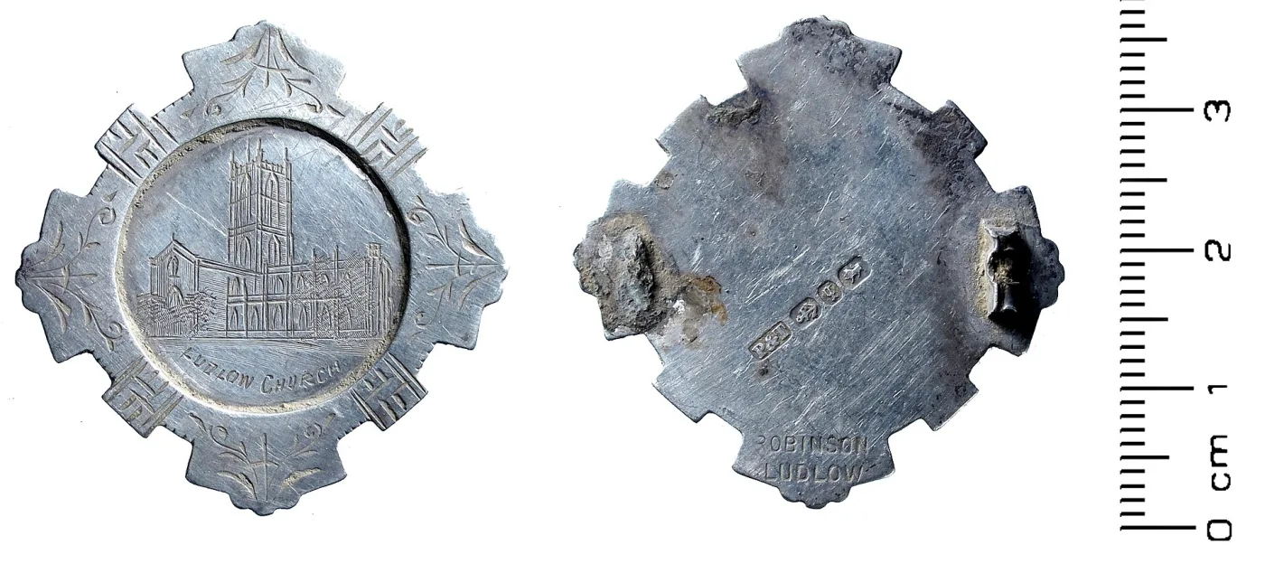 Front and back of a silver souvenir brooch engraved Ludlow Church, the back showing hallmarks, the maker's name Robinson Ludlow, and two rough solder scars where the hinge and catch have broken away