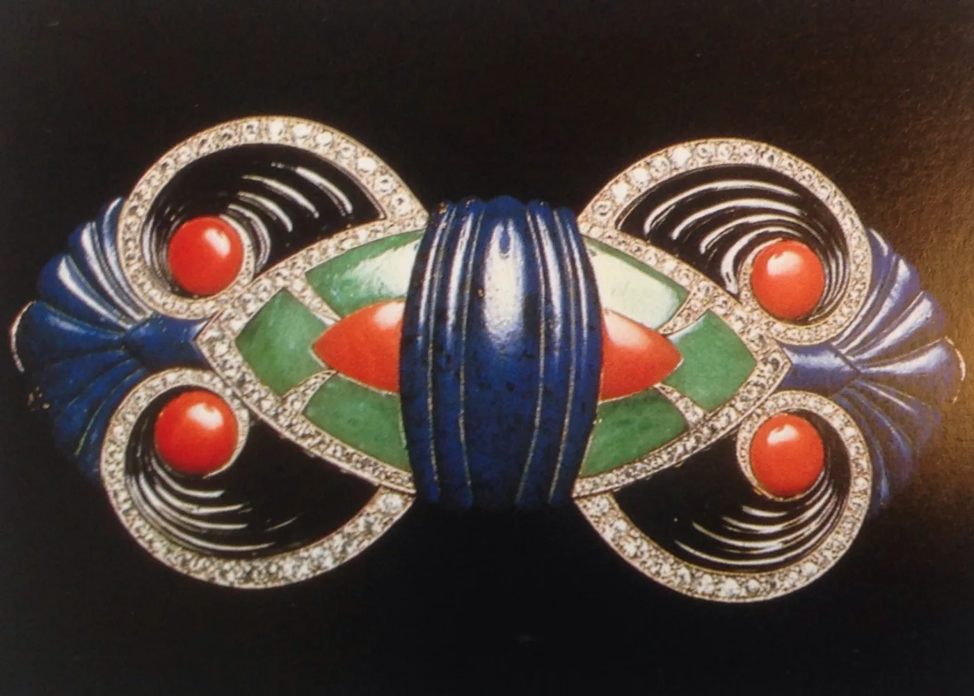 Art Deco buckle worked in coral red, lapis blue and green enamel around a central band of small pave diamonds, built from strict geometric blocks