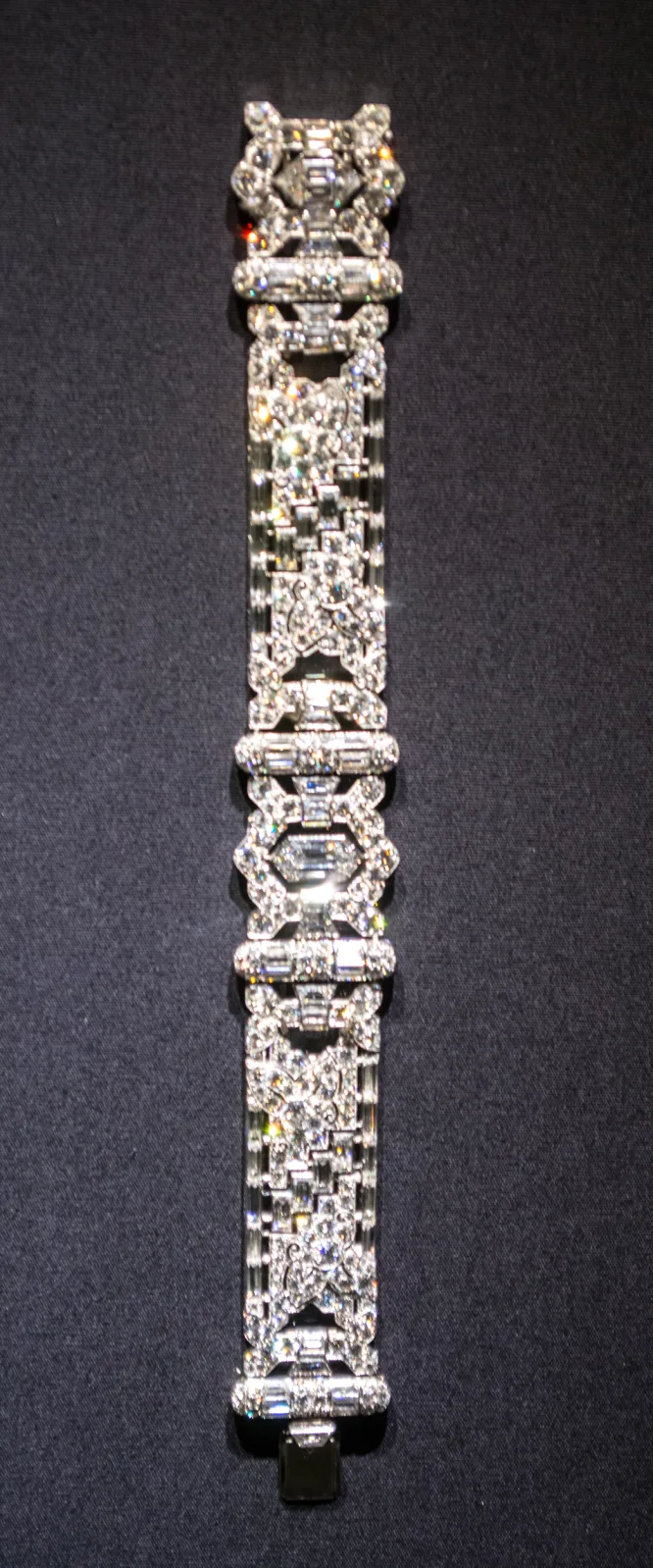 Narrow bracelet of linked geometric plaques densely set with small white diamonds, photographed against a black ground