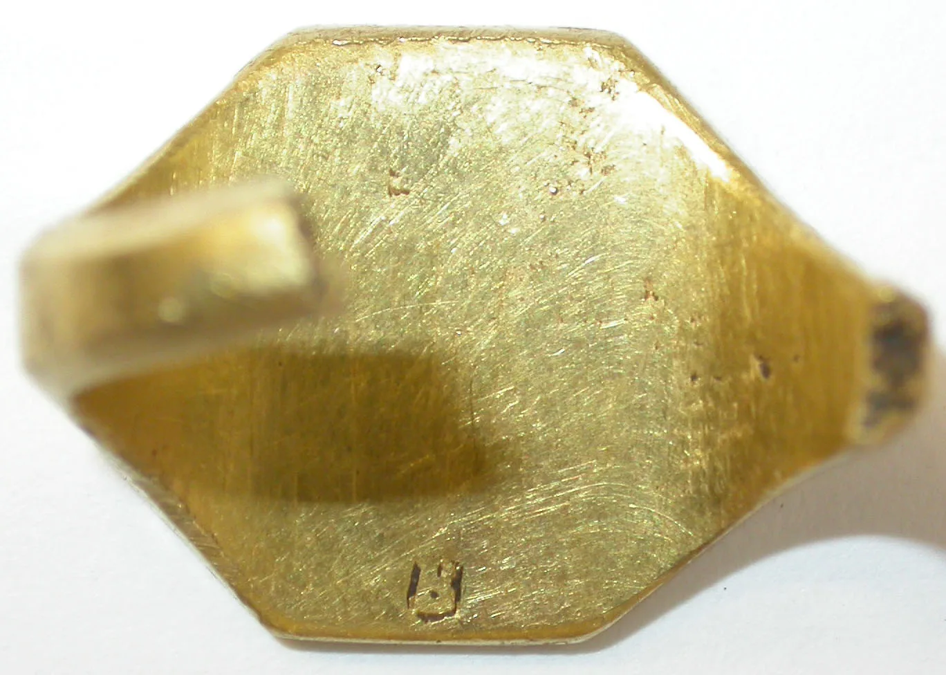 Close-up of the back of a gold signet ring, with a single small mark struck into the flat underside of the bezel