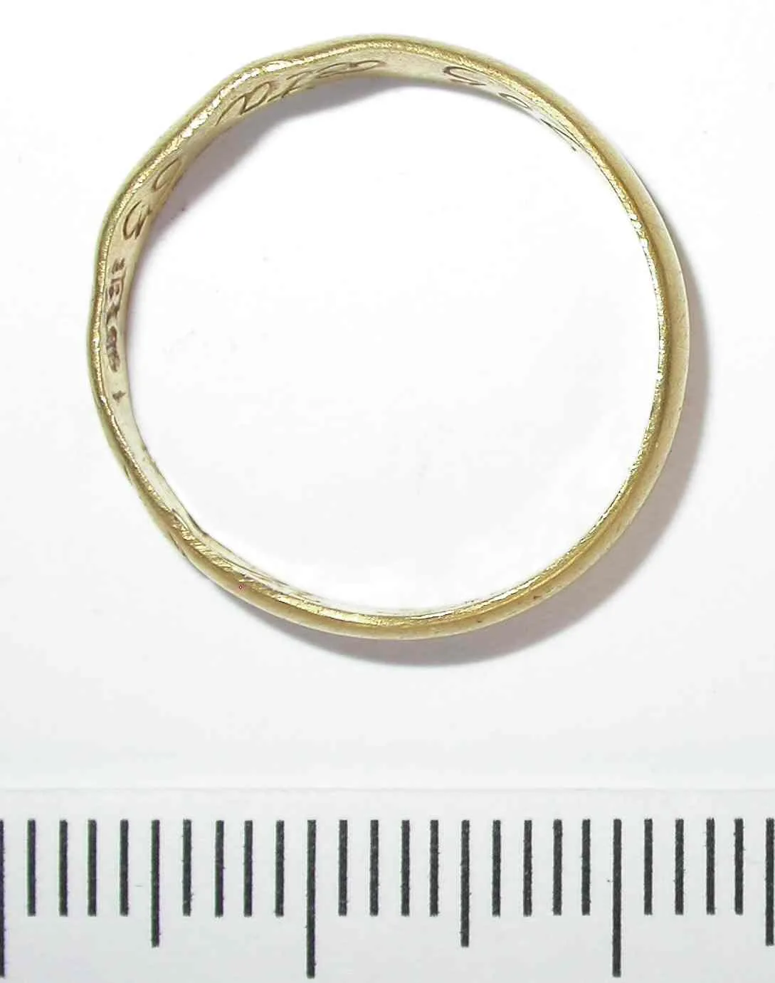 Plain gold hoop with an inscription running around the inner surface, photographed above a millimetre scale